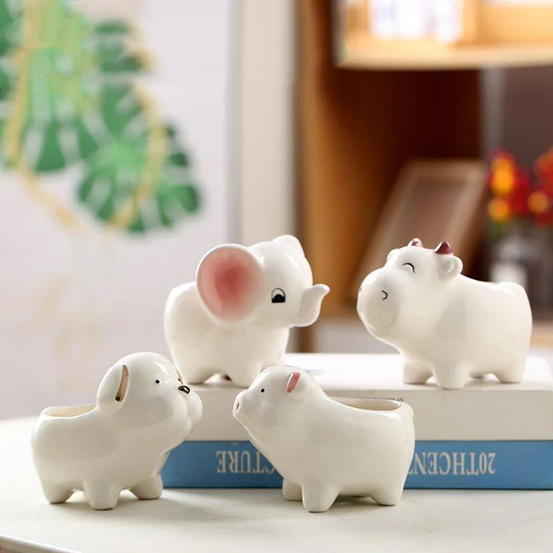 Four white ceramic animal planters displayed on a book