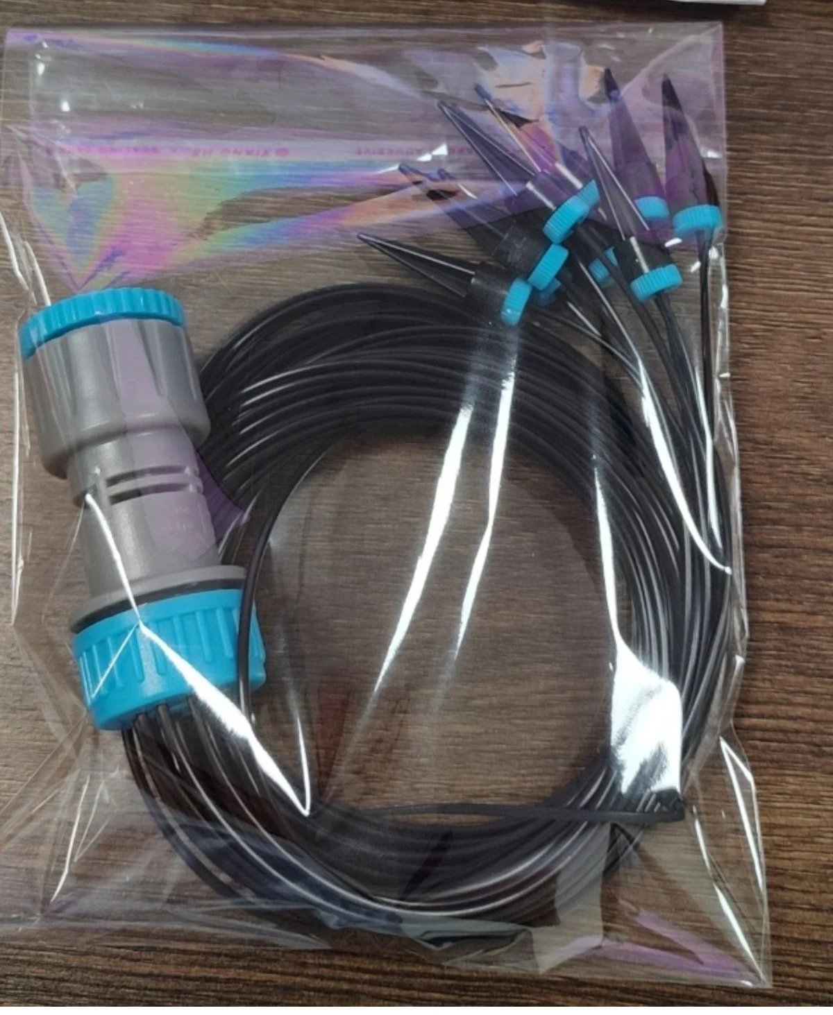 Drip irrigation kit packaged in a clear plastic bag on a wooden table