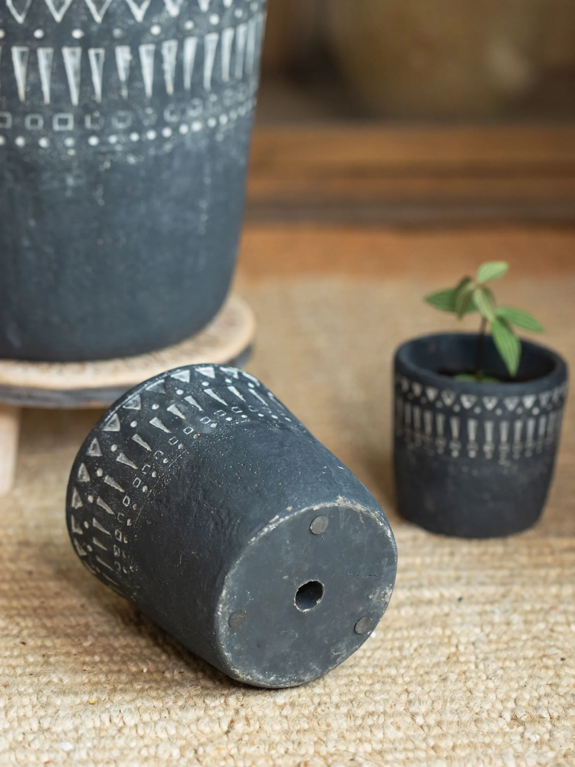 Dark gray concrete planter showing drainage hole and foot pads