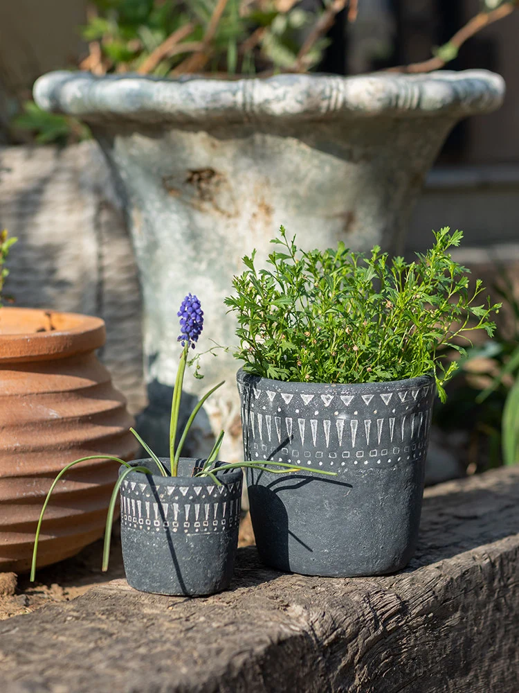 Dark gray concrete planters with green plants outdoors