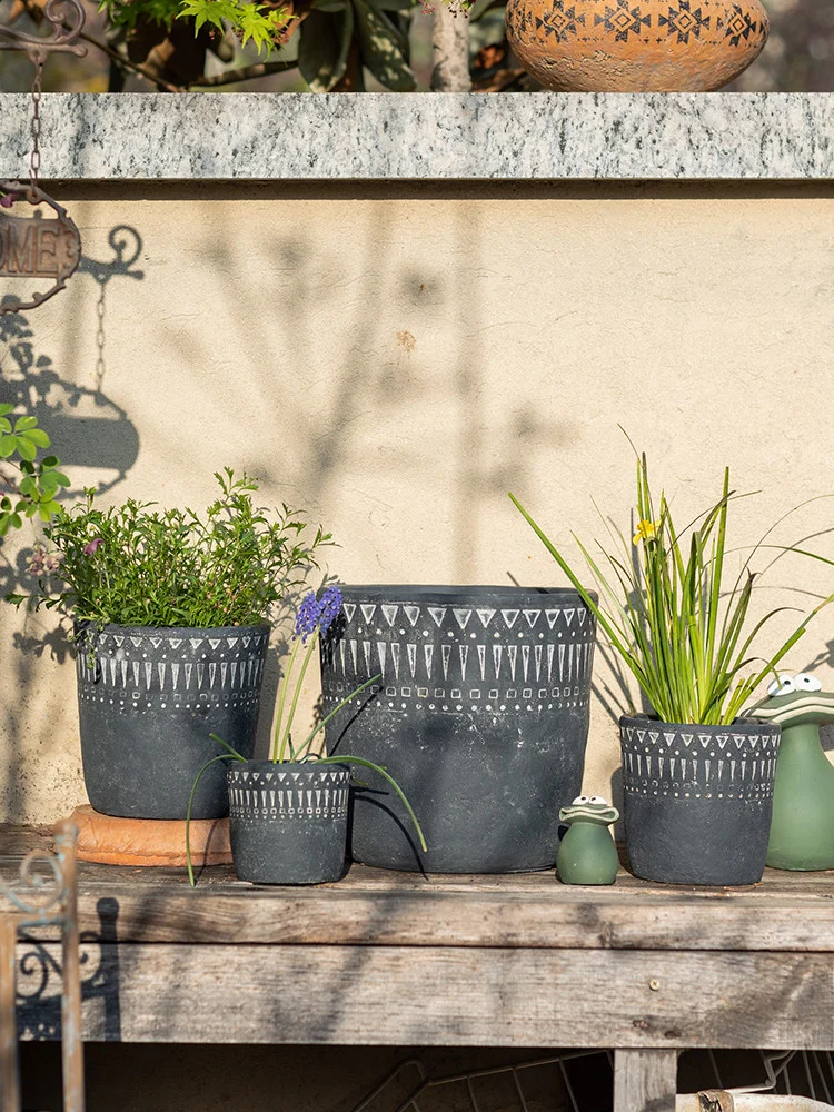 Collection of dark gray concrete planters on a wooden bench