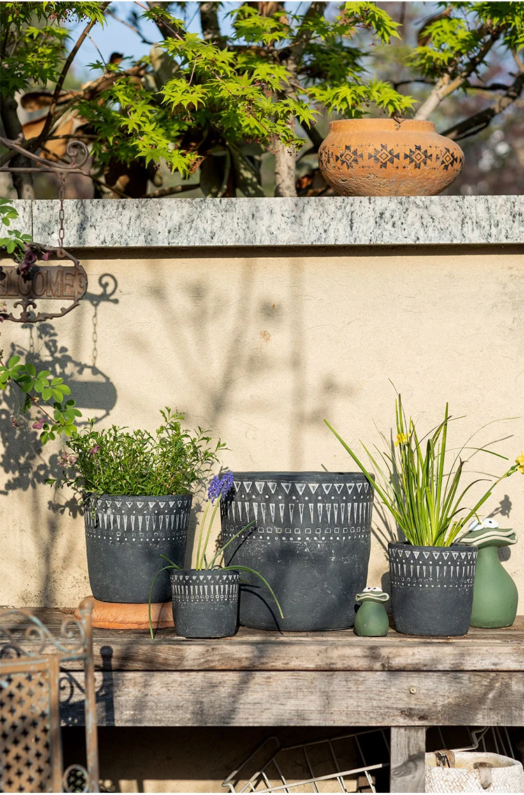 Dark gray concrete planters on a wooden bench outdoors