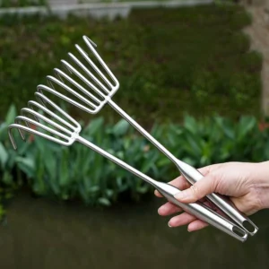 Two stainless steel hand rakes held outdoors against a green background